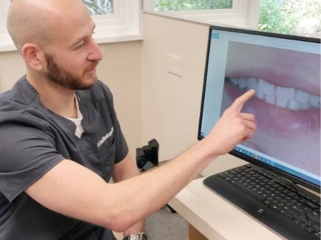 Dentist pointing to image of teeth on screen