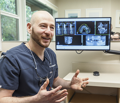 Doctor David talking next to a computer showing dental x-rays