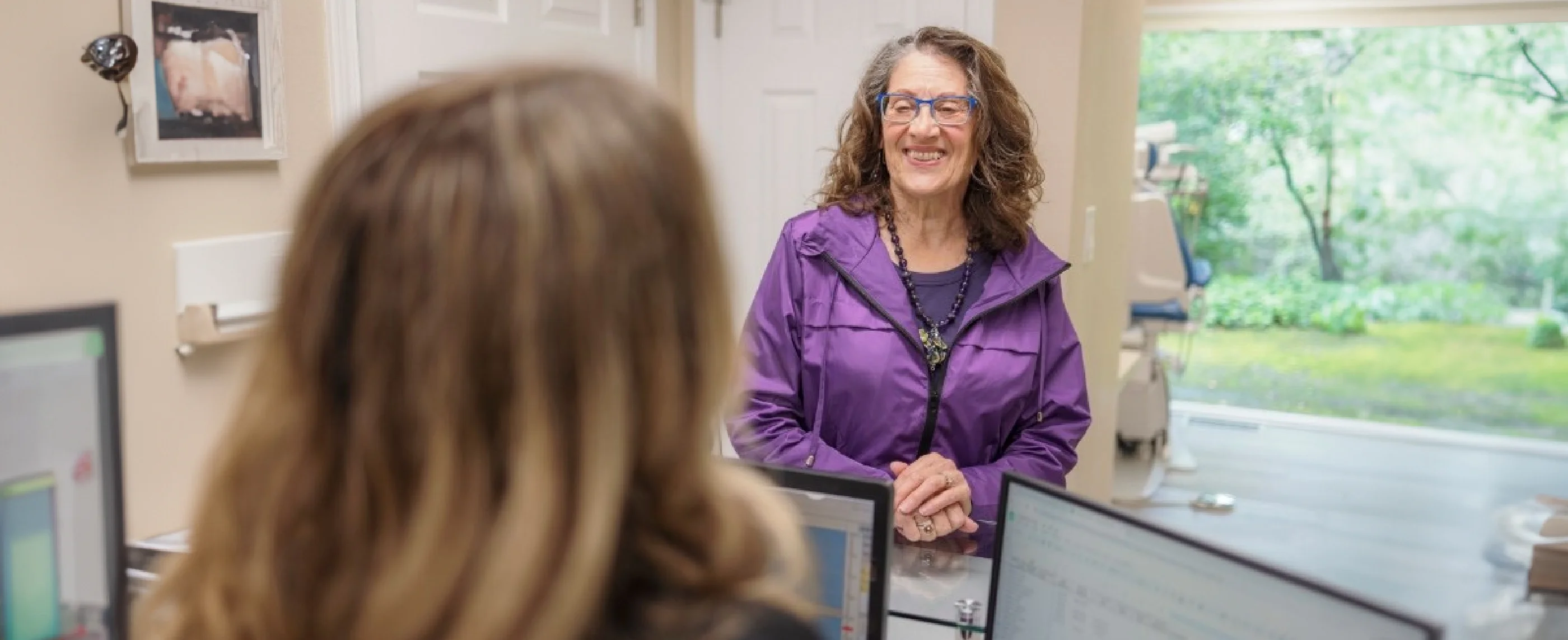 Woman with glasses talking to dental patient