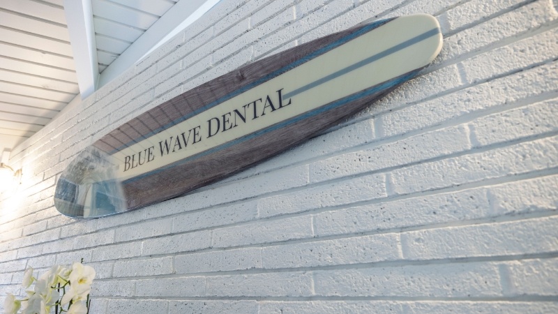 Surfboard reading Blue Wave Dental on wall