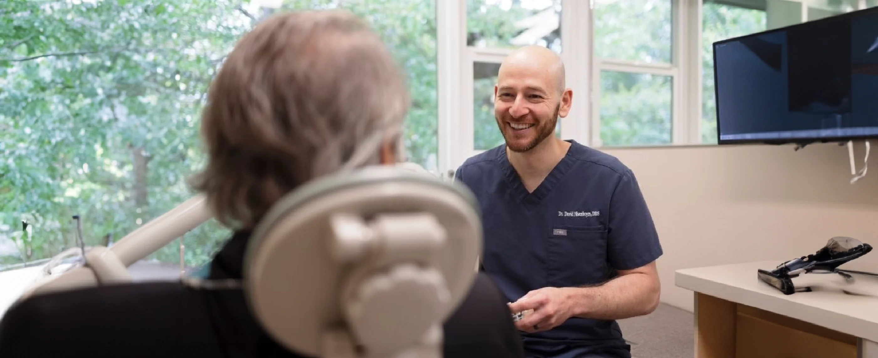 Patient in dental chair facing smiling dentist