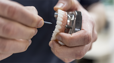 Dentist placing a dental implant in a model of the teeth